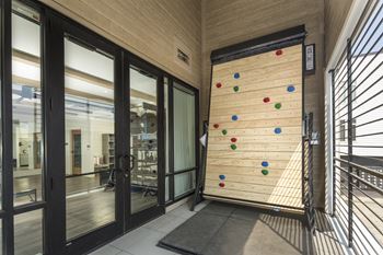 a climbing wall in the lobby of a building with glass doors